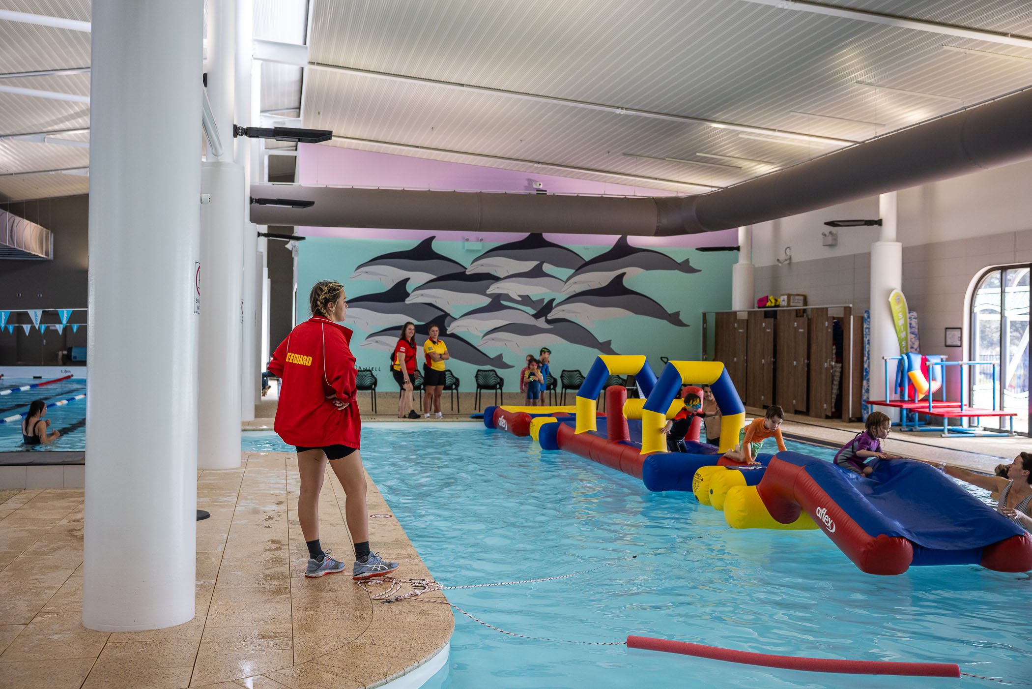 A lifeguard oversees children playing on an inflatable.