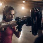 Woman exercising with a coach on a boxing training in a health club