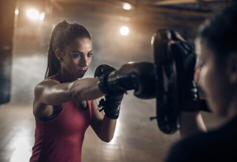Woman exercising with a coach on a boxing training in a health club