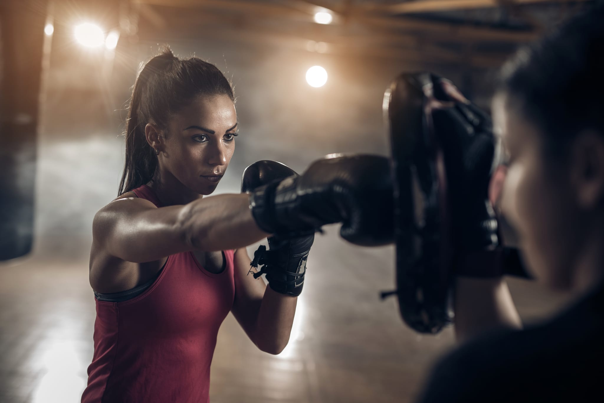 Woman exercising with a coach on a boxing training in a health club